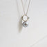 A 925 silver pendant inspired by natural forms like leaves has a large grey freshwater pearl hanging from the base of it.