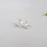 A 10 mm silver bird in flight- earring with a small white pearl placed at the bottom of the bird's breast, tucked under the tail feathers.