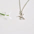 A 10 mm Hummingbird depicted in flight hangs from a silver chain. A tiny pearl sits at the bottom of the bird's breast.