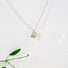 A delicate 10 mm flower constructed with 5 silver daisy like petals and 3 14 karat yellow gold balls that sit in the centre of the flower that suggest the stamens of the flower. Each petal is hand formed and stamped to resemble a petal's form. The flower is easily recognizable and hangs from a 16 " silver curb chain.