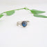 A silver ring featuring textured ribbons of metal that create the band. Highlighted by a green blue Labradorite stone.
