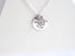 Large coin shaped silver medallion 2 cm in diameter with cut out leaf shapes and a small pearl accent.