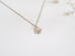 A delicate 10 mm flower constructed with 5 silver daisy like petals and 3 14 karat yellow gold balls that sit in the centre of the flower that suggest the stamens of the flower. Each petal is hand formed and stamped to resemble a petal's form. The flower is easily recognizable and hangs from a 16 " silver curb chain.
