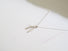 A wishbone shaped sterling silver pendant accented with a small 3 mm white freshwater pearl at the heart of the wishbone .