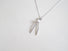 A wishbone shaped sterling silver pendant accented with a small 3 mm white freshwater pearl at the heart of the wishbone .