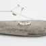Silver ring with a geometric hexagon design on a stone surface with a blurred background