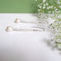 A pair of long and slender icicle like silver earrings featuring a white 5 mm oval pearl attached to the bottom tip.