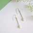 A pair of long and slender icicle like silver earrings featuring a white 5 mm oval pearl attached to the bottom tip.