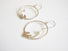 A pair of hoop earrings with sprig of laurel leaves dangling and a white round pearl which is at the end of the sprig leaf.