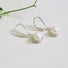 A round 6 mm white genuine pearl is set into an organic shaped rim of silver which is suspended from a silver ear hook.