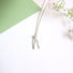 Awishbone shaped sterling silver pendant accented with a small  3 mm white freshwater pearl at the heart of the wishbone .