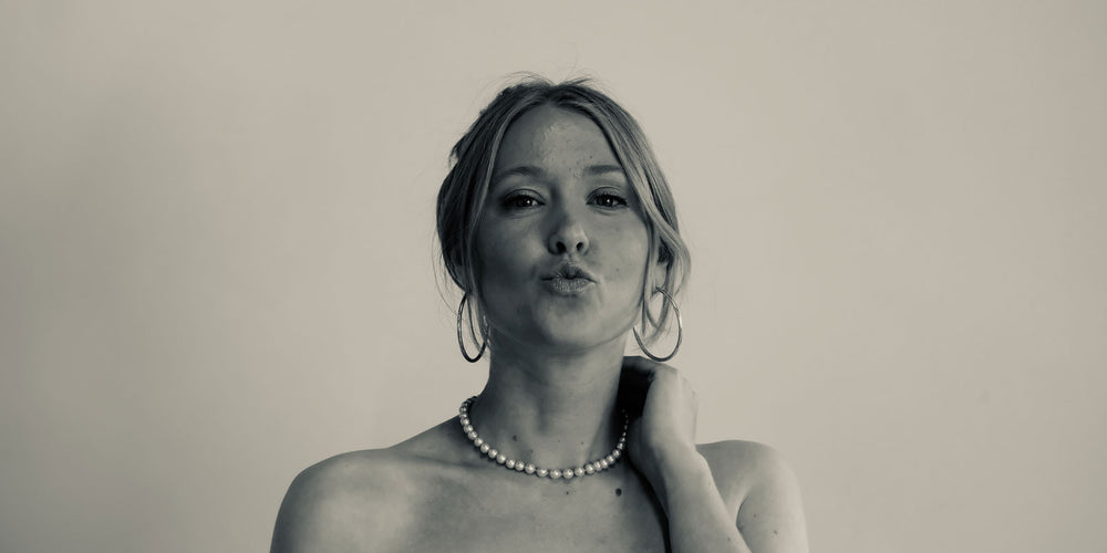 woman blows a kiss wearing large white pearl chocker and oversized silver hoops