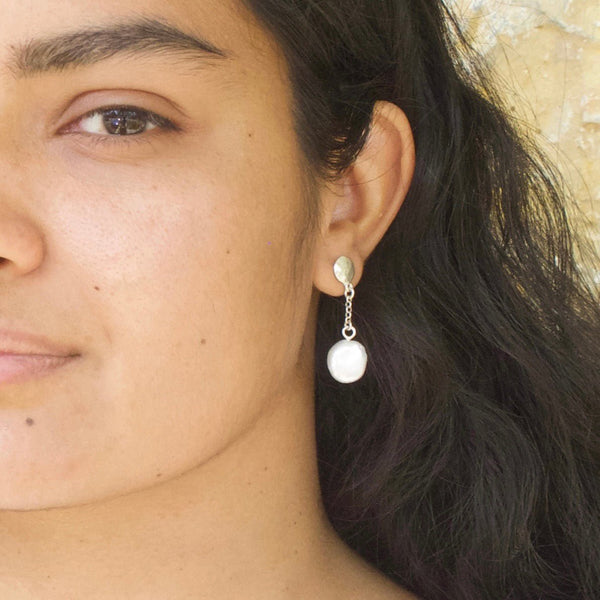 model shows a freshwater white coin pearl earring hanging from a silver disc and short fine chain.