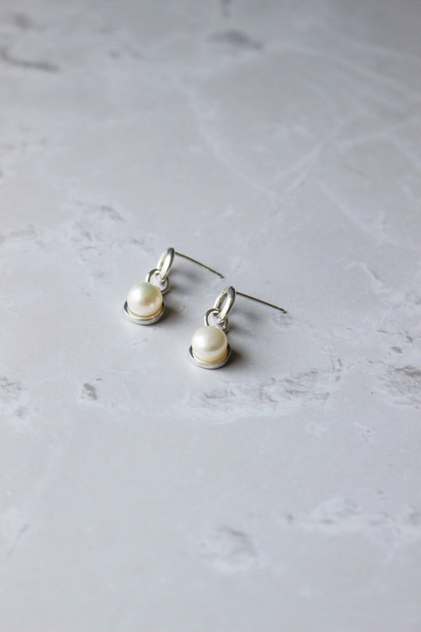 6 mm freshwater pearl earrings nestle in a halo of silver dangles from a soft modern round ring of silver with an ear posts