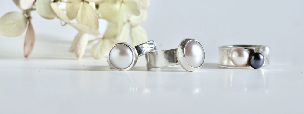 a collection of solitaire pearl rings. Various pearl sizes and band widths make up the silver rings. Each one unique