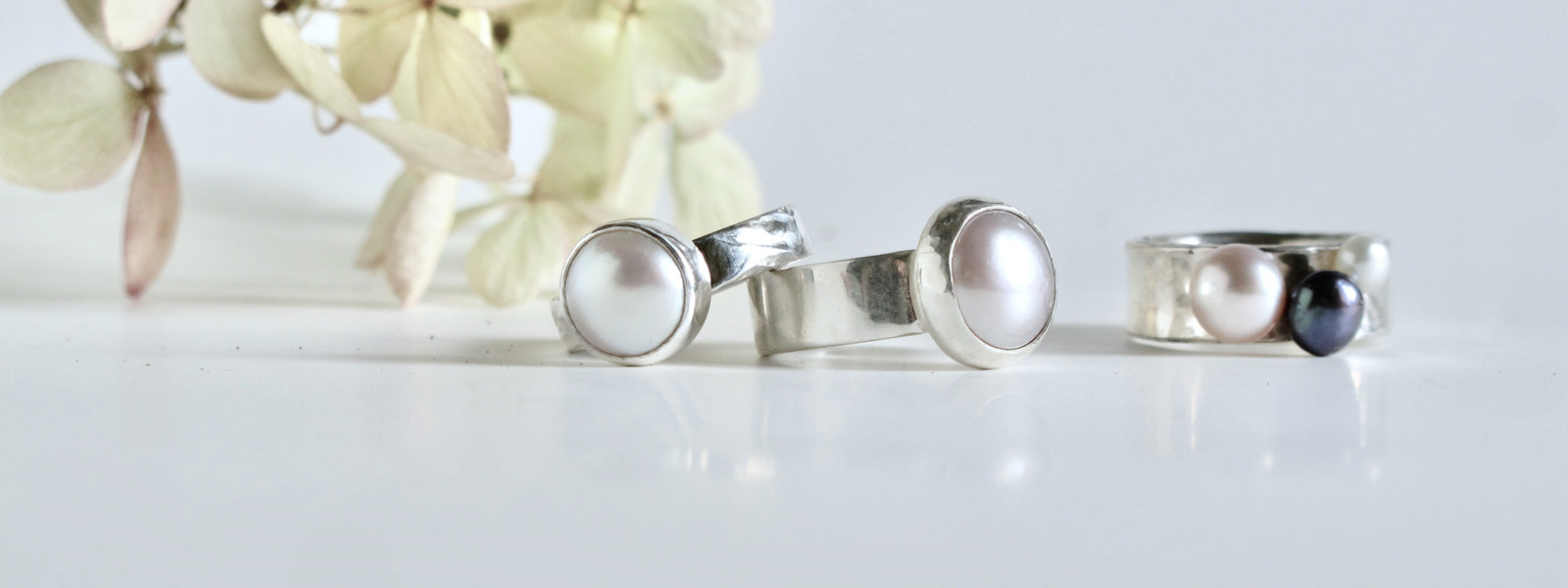 a collection of solitaire pearl rings. Various pearl sizes and band widths make up the silver rings. Each one unique