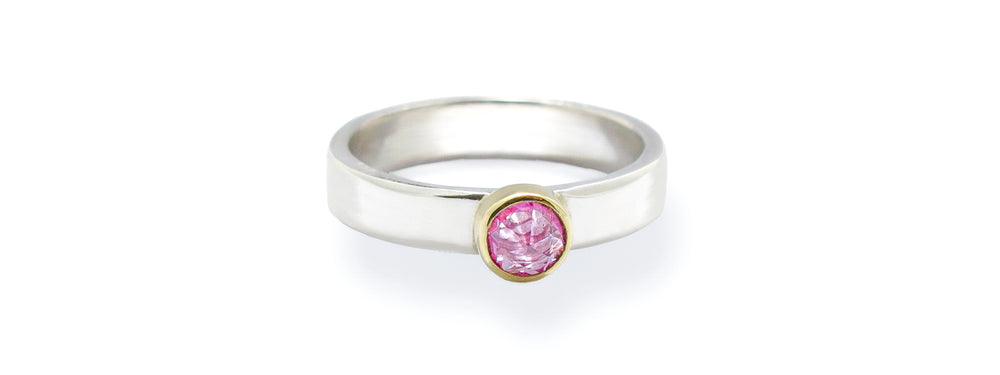 a pink rose cut sapphire solitaire ring. Sapphire is set onto a delicate sterling silver band and trimmed with a gold bezel setting. 