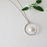 Reiki imbued 10 mm genuine round white coin pearl  that sits in the middle of the circle on a  fine silver post that attaches to the base of the circle.