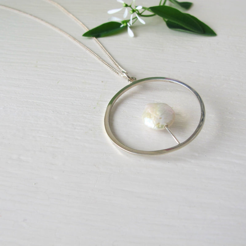 Reiki imbued 10 mm genuine round white coin pearl  that sits in the middle of the circle on a  fine silver post that attaches to the base of the circle.