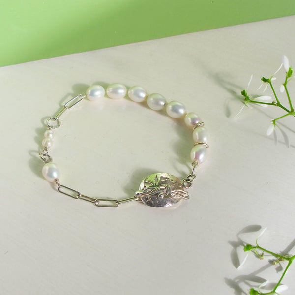 Genuine hand strung pearl bracelet with hand made round silver clasp with pierced botanical motifs.