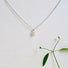 A sterling silver chain has a delicate and small  X shape charm hanging from it. The X is designed to symbolize a Kiss! The kiss is sealed with a 3 mm round genuine pearl that sits in the middle of the X.  The pendant measures approximately 10 mm x 8 mm