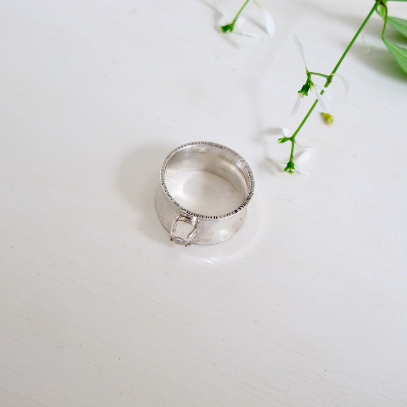 This ring is called Big Beauty and lives up to its name with a 10 mm wide, slightly concave band. Nestled in the middle of the band is a prong set 6 mm rose-cut white topaz stone.  It is a very modern and elegant looking ring 