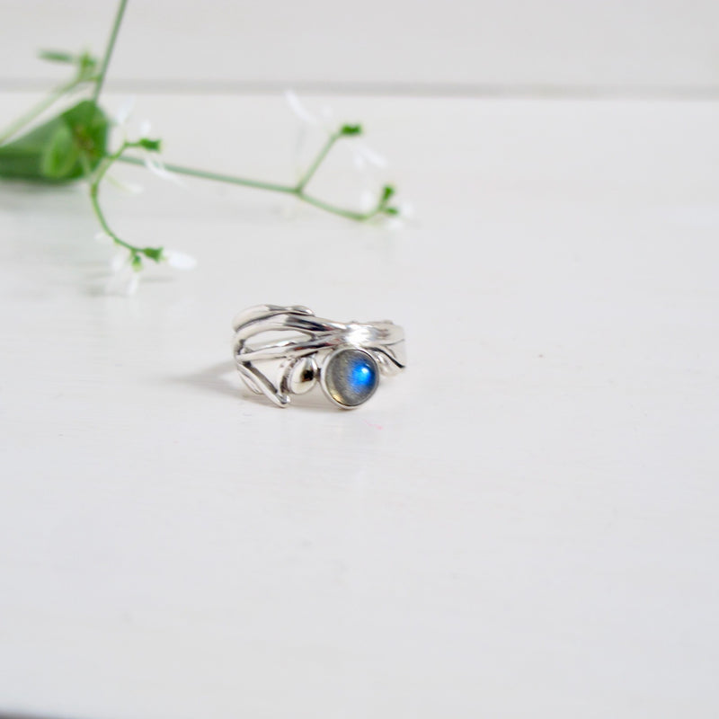 A striking sterling silver ring with an Art Deco feel. Vines and leaves  intertwine around  the finger to create the band  This ring is highlighted with an iridescent blue green 6 mm Labradorite gemstone set in sterling silver.