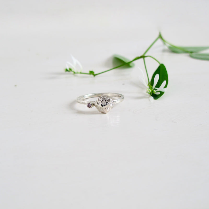A delicate 2 mm silver ring with a handmade  silver moon rock like stone set in the centre.Next to the Moon rock, slightly off set from the centre, is a bezel set genuine 2 mm violet sapphire. v
