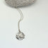 A  sterling silver pendant composed of three intertwined maple leaves which are contained by an open circle of silver. 
