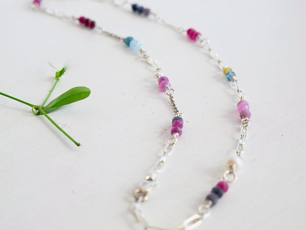  Authentic gemstones: Blue topaz, Garnets, Rhodolite garnets. Rubies  Sapphires and genuine pearls are arranged in an artful and asymmetrical design on a sterling silver paper clip link chain