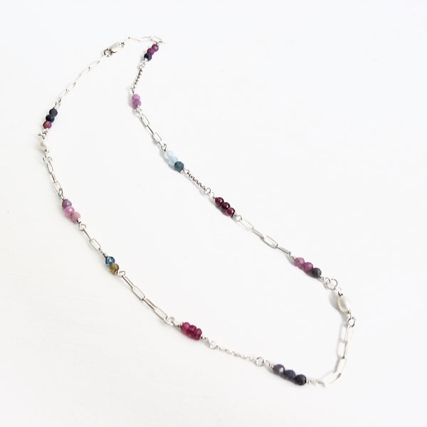 Authentic gemstones: Blue topaz, Garnets, Rhodolite garnets. Rubies  Sapphires and genuine pearls are arranged in an artful and asymmetrical design on a sterling silver paper clip link chain