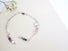 A silver link bracelet with blue and red sapphire beads and a leaf and twig bead link is incorporated into the link chain bracelet .