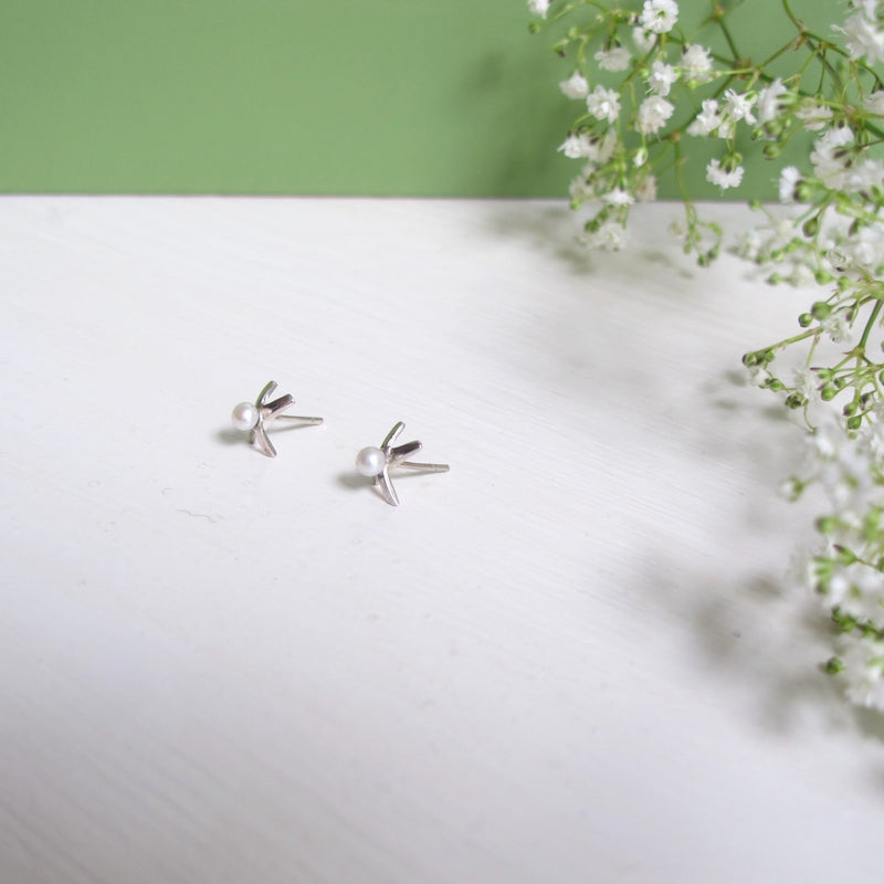 A delicate pair of reiki imbued silver studs which are shaped in the form of an X' to symbolize a Kiss. A small consciously sourced pearl in the middle of the X shape