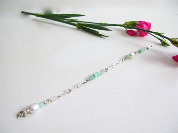 A silver bracelet composed of a pleasing mixture of Peruvian Opal beads and genuine white pearls. The bracelet is made with sterling silver    paperclip chain.  Measures 7.50 " long. Can be adjusted 