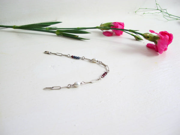 A paper clip link bracelet made up of Blue Sapphire, Genuine Pearl, and Deep Red Garnet beads.  Measures 7.50 "  Can be adjusted to size. 