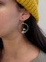 A pair of hoop earrings with sprig of laurel leaves dangling and  a white round pearl which is at the end of the sprig leaf.