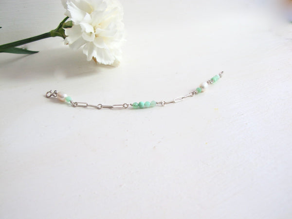 A silver bracelet composed of a pleasing mixture of Peruvian Opal beads and genuine white pearls. The bracelet is made with sterling silver    paperclip chain.  Measures 7.50 " long. Can be adjusted to size