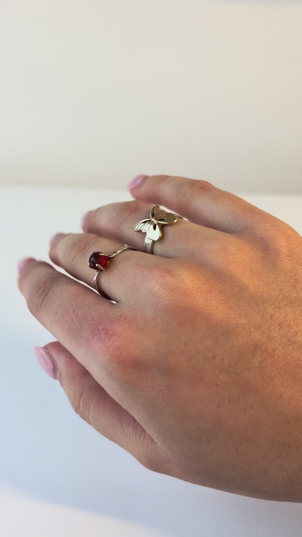 Woman wears a golden butterfly ring. She is moving her hand around to show of all sides of the butterfly ring