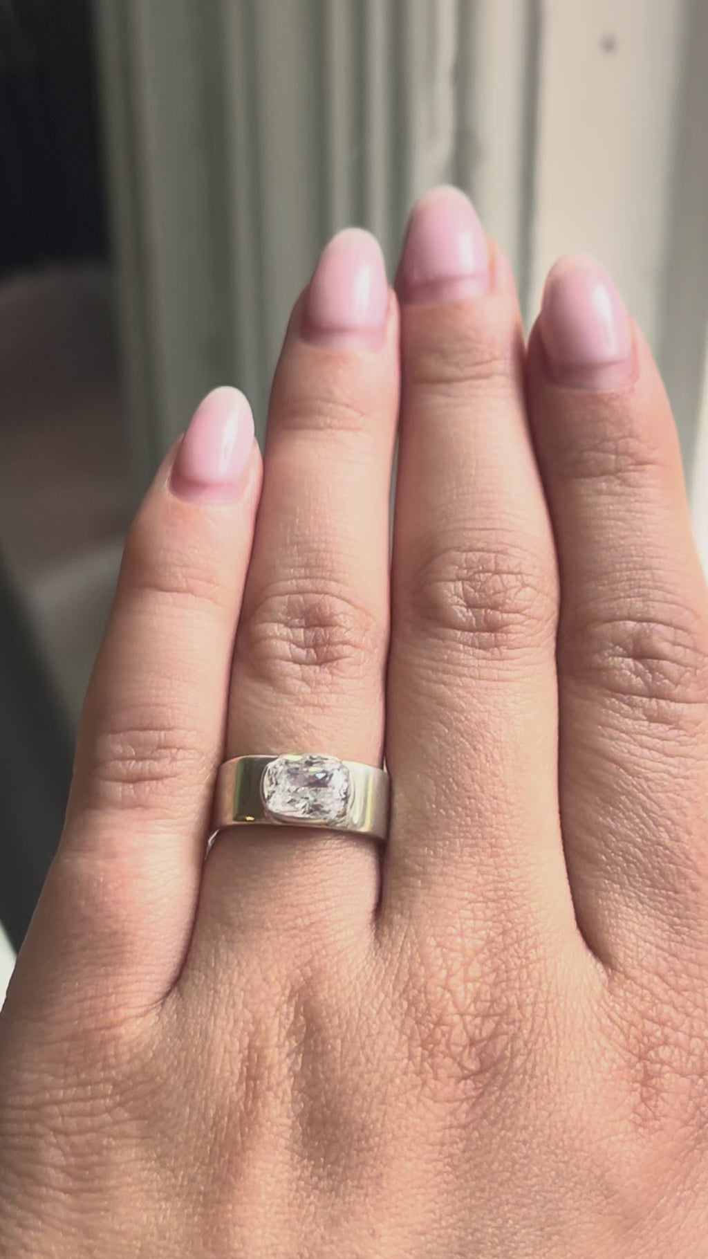woman with an oval diamond ring moves her hand to show off the diamond.