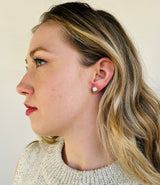 A soft silver halo ring stud has a  6-7 mm white button pearl attached to the top of the earring.