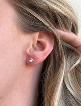 A consciously sourced, Reiki imbued handcrafted tiny silver crescent sits snug to the earlobe and frames a round white pearl.