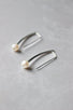 A slightly curved 1 " long silver bar hangs from the earlobe. At the bottom of the bar is a small white round pearl.