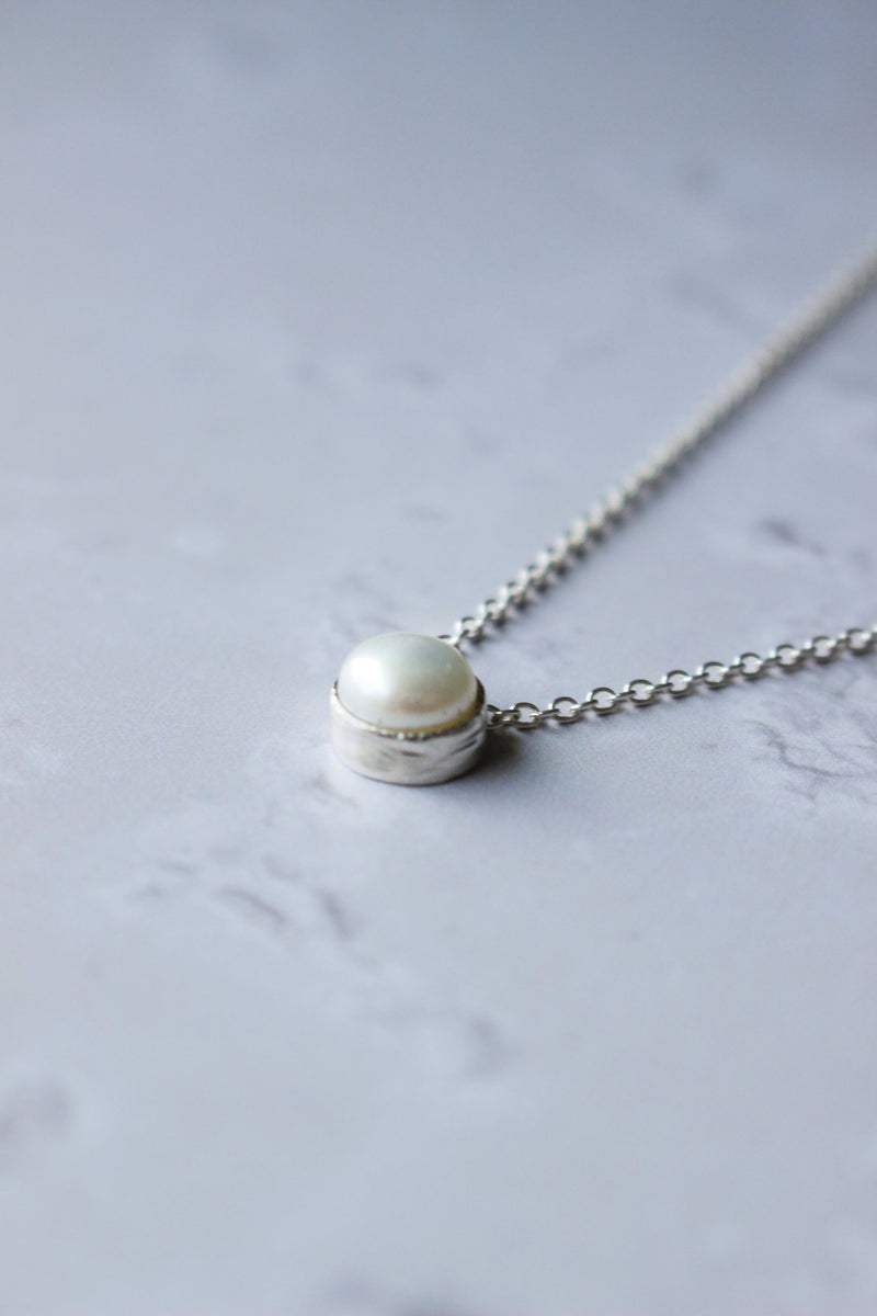An 8 mm genuine round pearl set in a silver casing. The pearl setting gives the illusion of floating on a 16" silver chain.