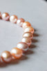 Freshwater round natural pearls ranging from off-white, soft pinks and lavender pinks form a neck-hugging hand knotted strand