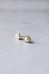 Small bowl shaped studs with a thin silver rim and 4 mm white pearl set in the centre of the disc.