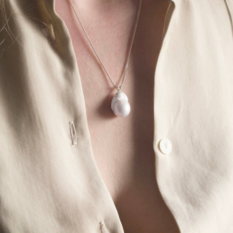 A large irregularly shaped freshwater Baroque pearl dangles from a sophisticated Reiki imbued sterling silver chain