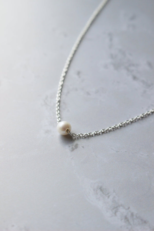 A 6 mm round white freshwater pearl threads on a fine silver chain to give the illusion it is floating.