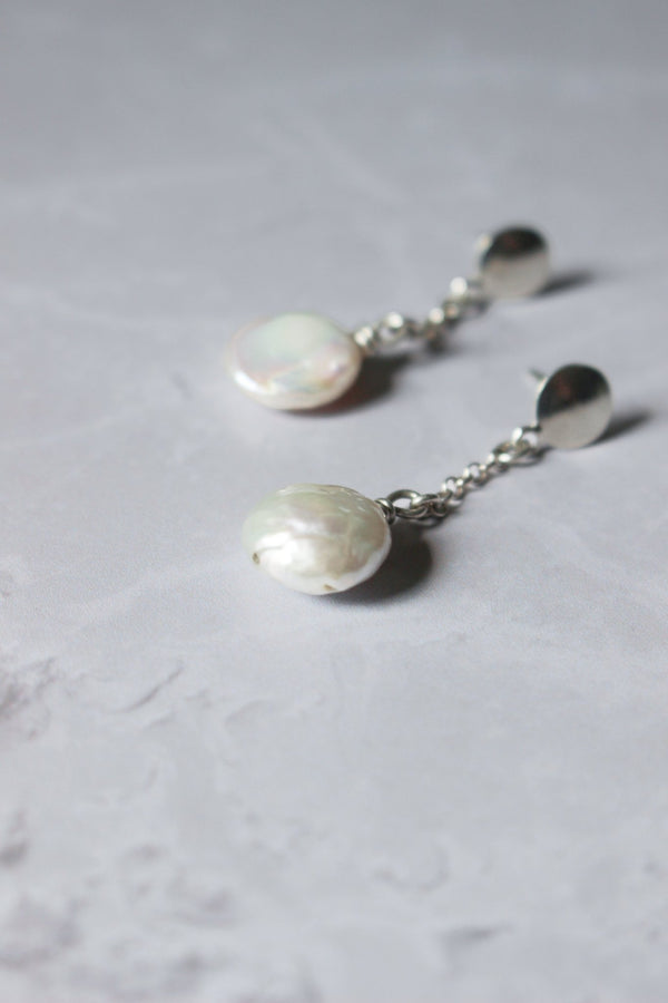 Freshwater white coin pearl earrings hang from a Reiki imbued silver chain that attaches to a small disc stud earring