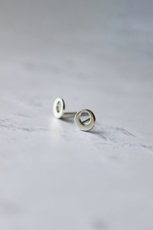 tiny open circle shaped silver stud earrings has a circular cutout to look like an  O.