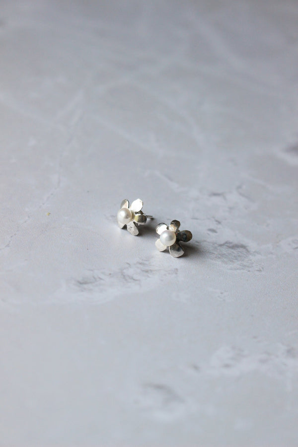 5 petal flower silver earring with petals arcing downward. The centre of the flower is a small round white freshwater pearl.